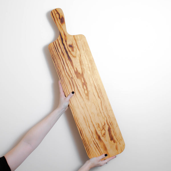 A person using a Bespoke 77 Large Pine Serving Board / Sharing Board as a sharing board during meal times.