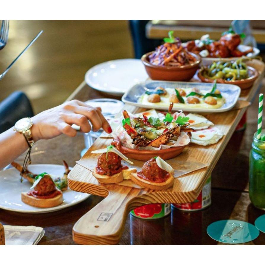 A Bespoke 77 large serving board / sharing board of food on a wooden table, perfect for meal times and sharing.