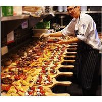 A chef preparing a tray of food on a Bespoke 77 Medium Pine Serving Board / Sharing Board in a kitchen.